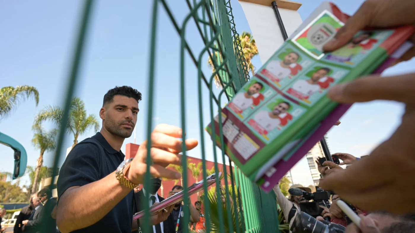 Iranian footballer Mehdi Taremi signs a Panini album before the team leave for the US in Tijuana, Mexico, on 20 June 2026 (AFP)