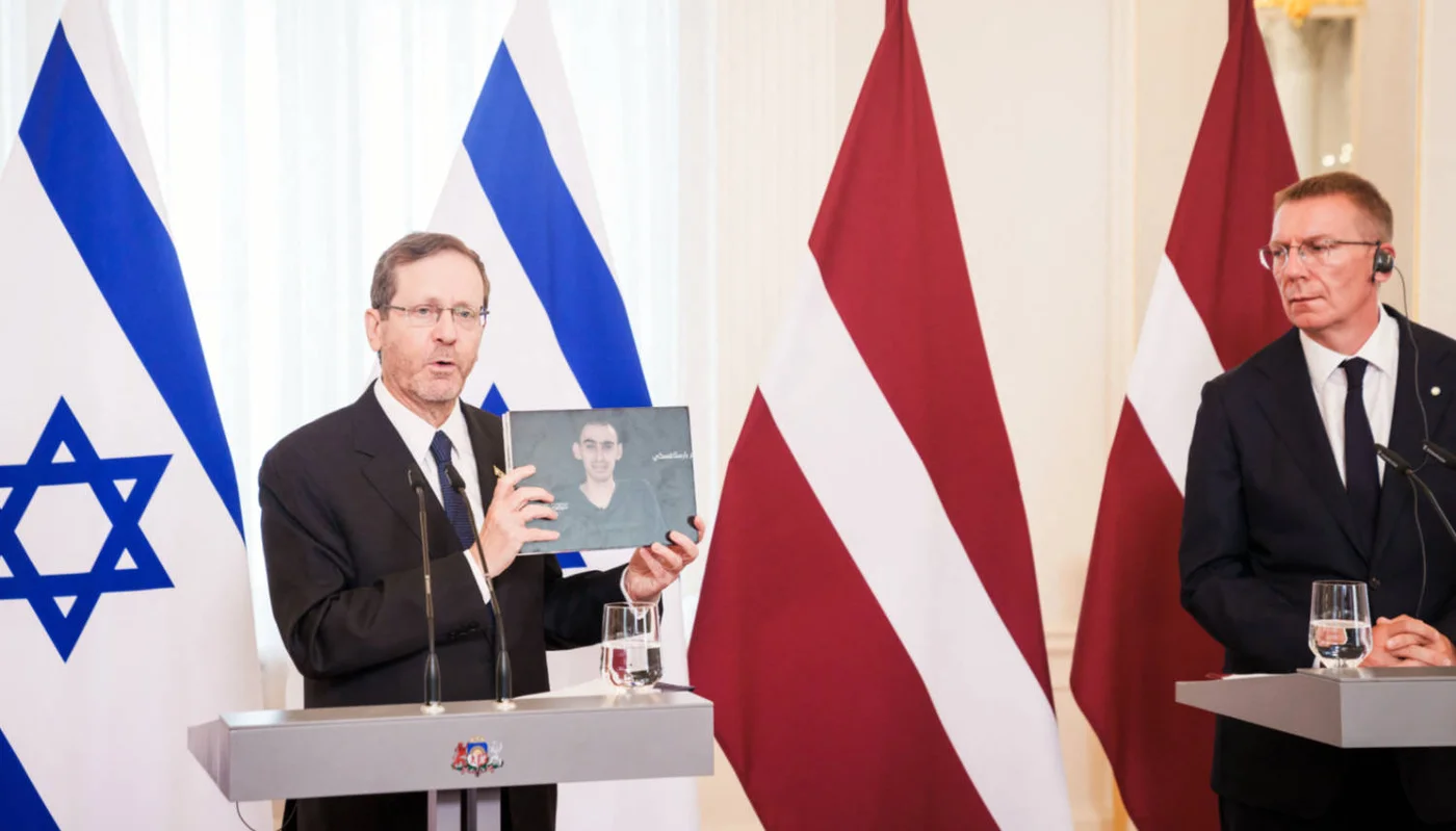 Israeli President Isaac Herzog holds a photo from a video showing Israeli hostage Rom Braslavski, during a joint press conference with Latvia's President Edgars Rinkevics in Riga, Latvia, on 5  August 2025 (AFP)