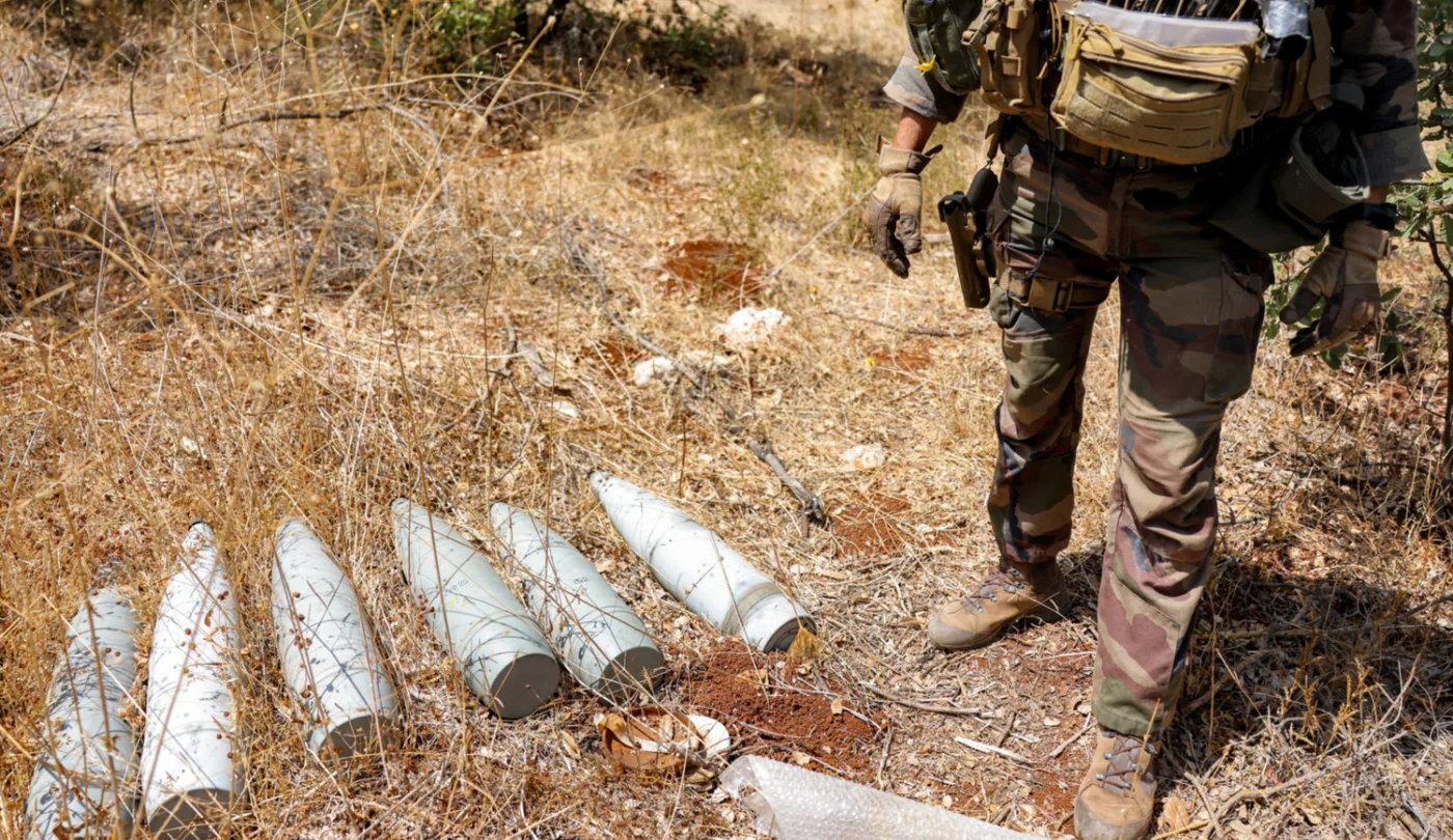 A UN peacekeeper stands by munitions formerly used by Hezbollah group in the Khraibeh Valley, south Lebanon, in August 2025 (AFP)