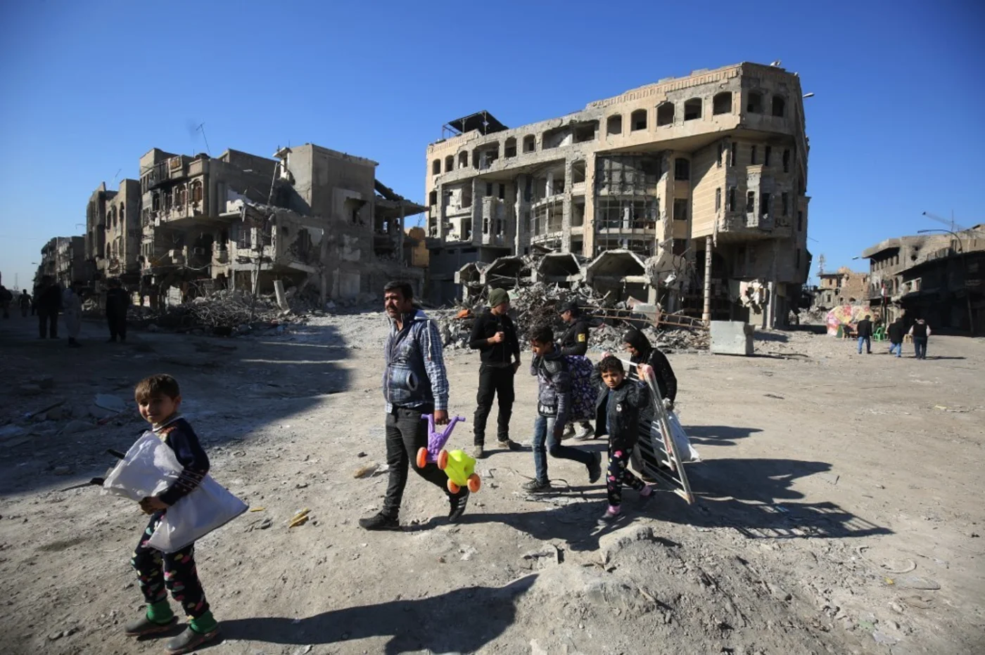 Iraqis civilians carry their belongings while walking on Nujaifi street in the old city of Mosul on9  January 2018 
