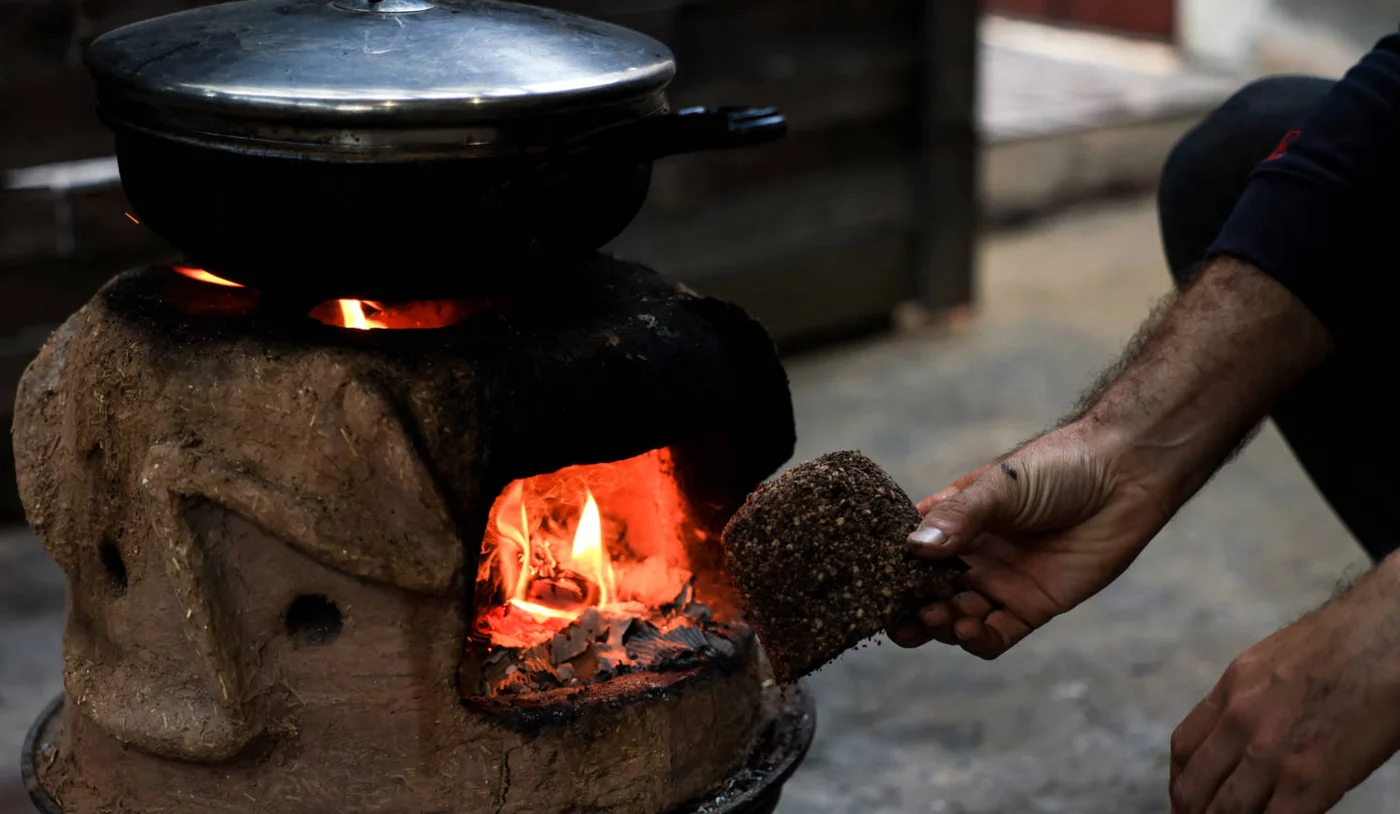 A Palestinian man manufactures a mixture of crushed olive pits to be used as fuel amid shortages in Rafah, Gaza, on 14 November 2023 (AFP)