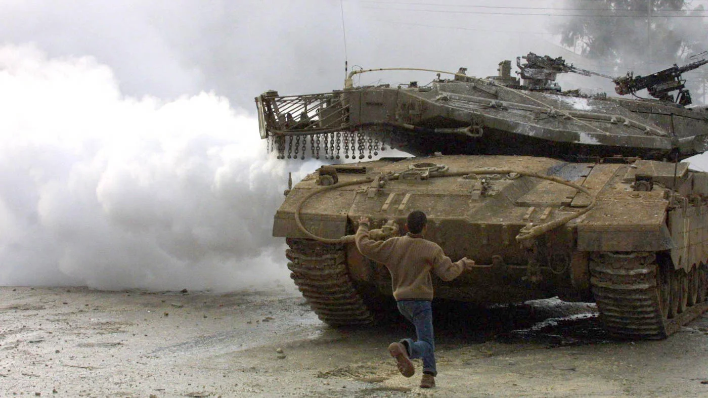 A Palestinian faces an Israeli tank in the Balata refugee camp, Nablus, West Bank, in January 2004 (AFP)
