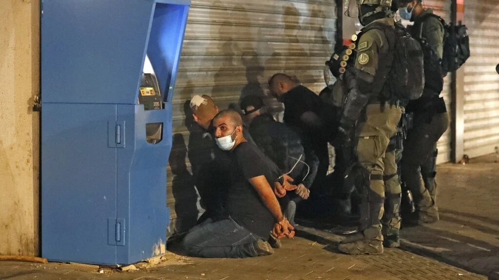 Israeli forces detain a group of Palestinian citizens of Israel in Lydd on 13 May 2021 after riots rocked the city (AFP)
