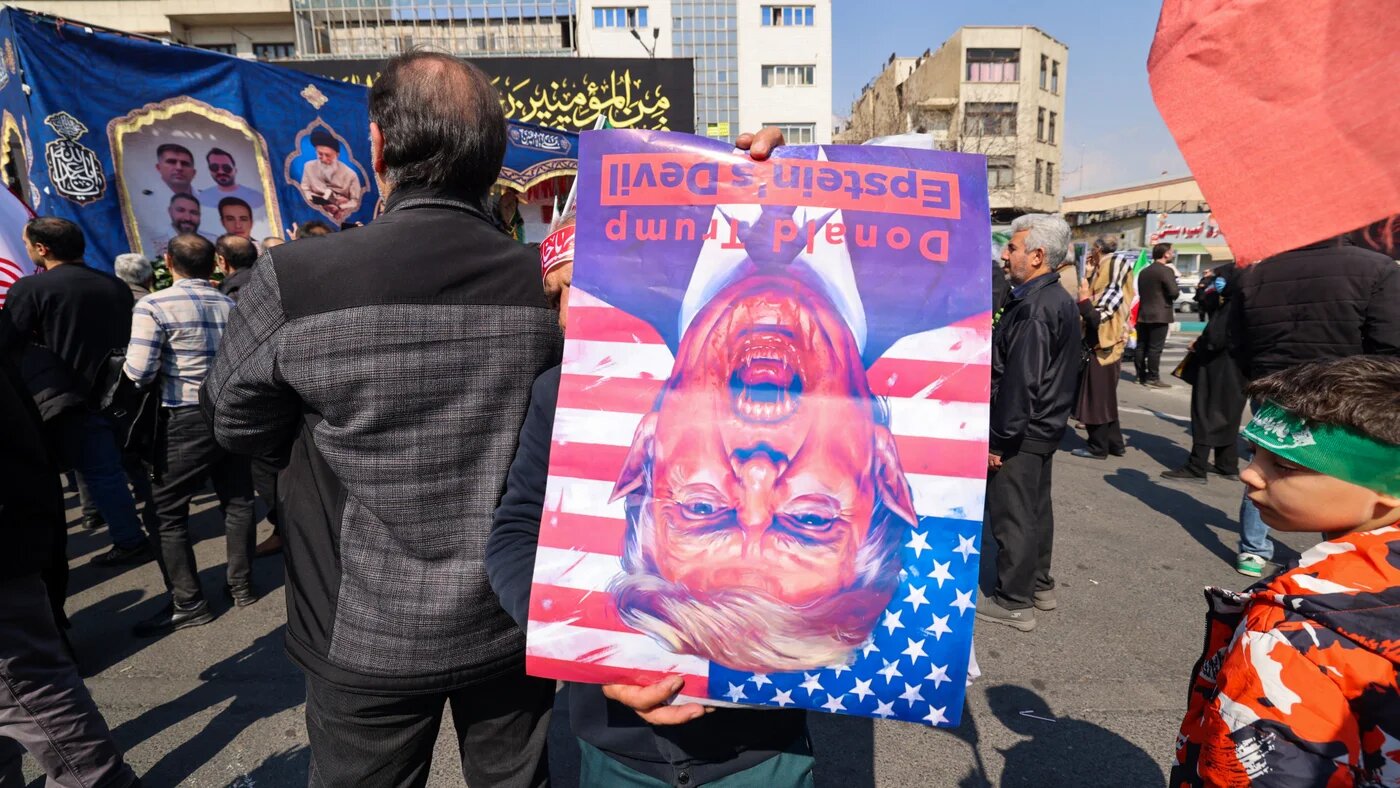 A person holds a poster depicting US President Donald Trump as mourners take part in a funeral procession for Iran's national security chief Ali Larijani, Basij commander Gholamreza Soleimani and Iranian sailors killed in recent strikes, in Tehran on 18 March 2026 (Atta Kenare/AFP)