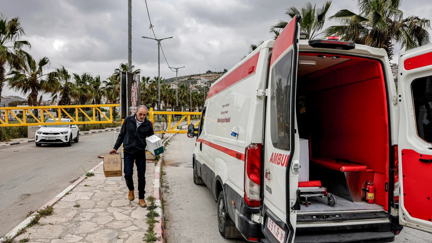 A man transports boxes of medication past an ambulance blocked at the entrance to Turmus Ayya, north of Ramallah in the occupied West Bank, on 6 May 2026 (AFP)