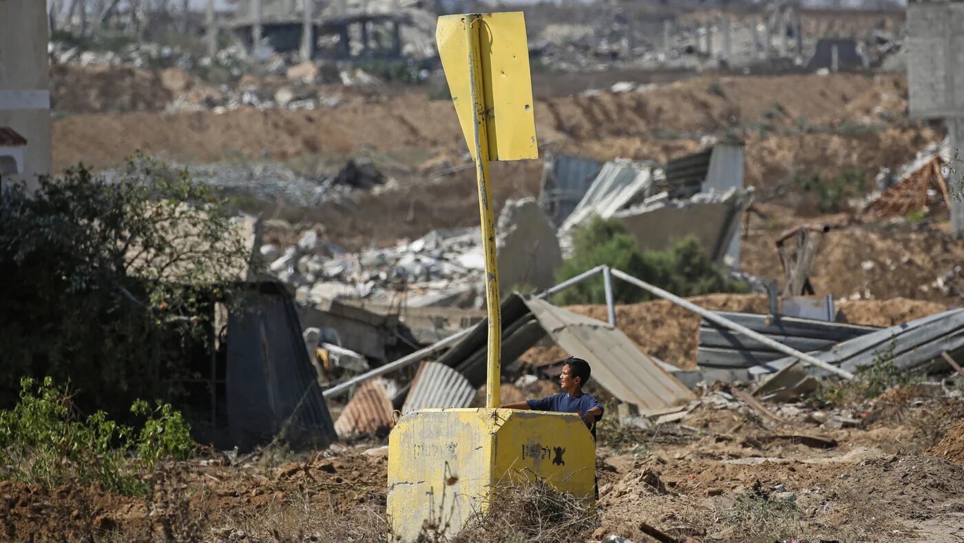 A Palestinian boy stands beside a concrete block marking Israel’s so-called Yellow Line in the east of Deir al-Balah, central Gaza, on 22 July 2026 (Eyad Baba/AFP)