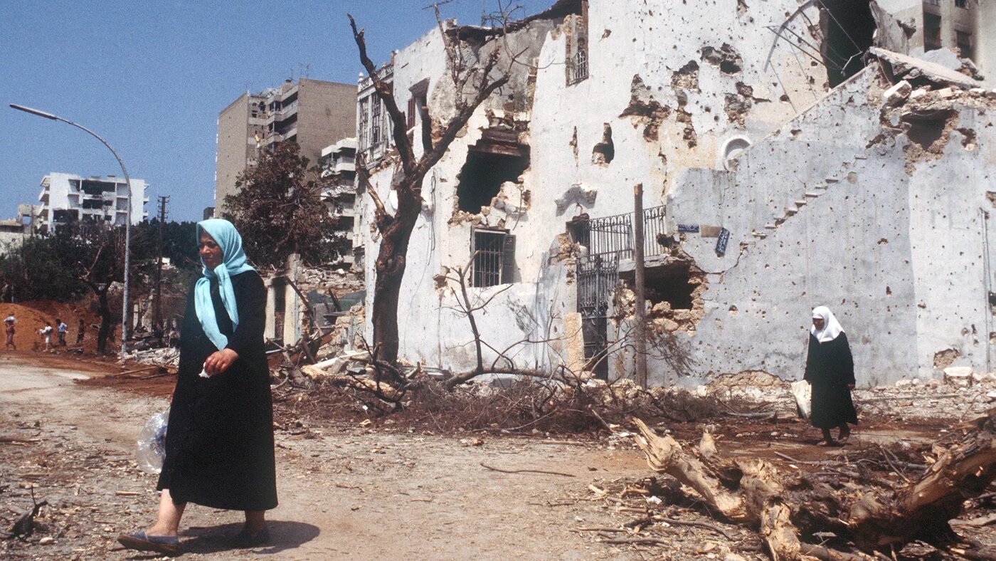 Two women walk through a West Beirut street devastated by Israeli shelling during the siege of the city on 24 July 1982 (Dominique Faget/AFP)
