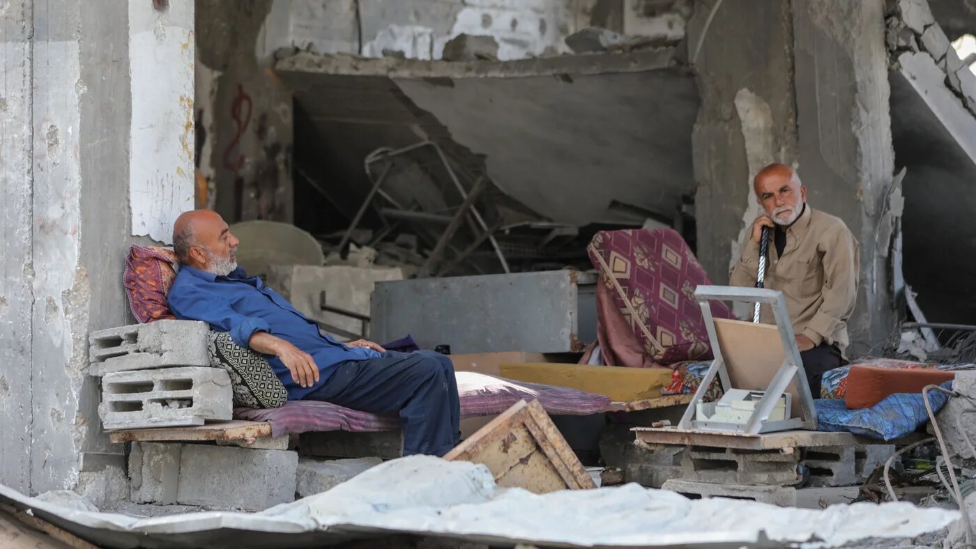 Two Palestinian men sit amid the rubble of their home in Gaza City that was targeted by Israeli fighter jets on 6 April, 2024 (MEE/Mohammed al-Hajjar)