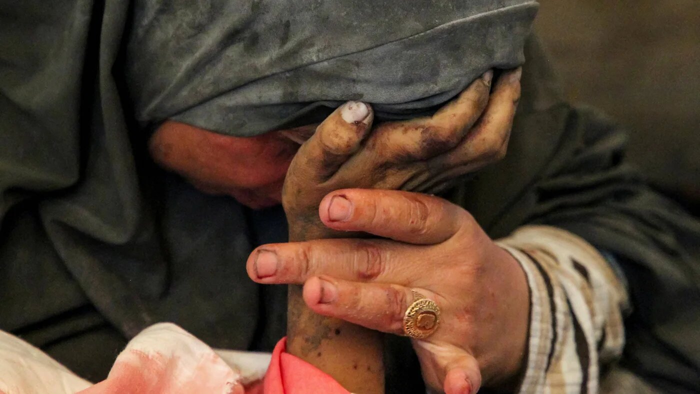 Palestinian woman Buthayna Abu Jazar reacts as she holds the hand of her son Hazma, who was killed in an Israeli strike in Rafah, in the southern Gaza Strip 9 May 2024 (Reuters/Hatem Khaled)