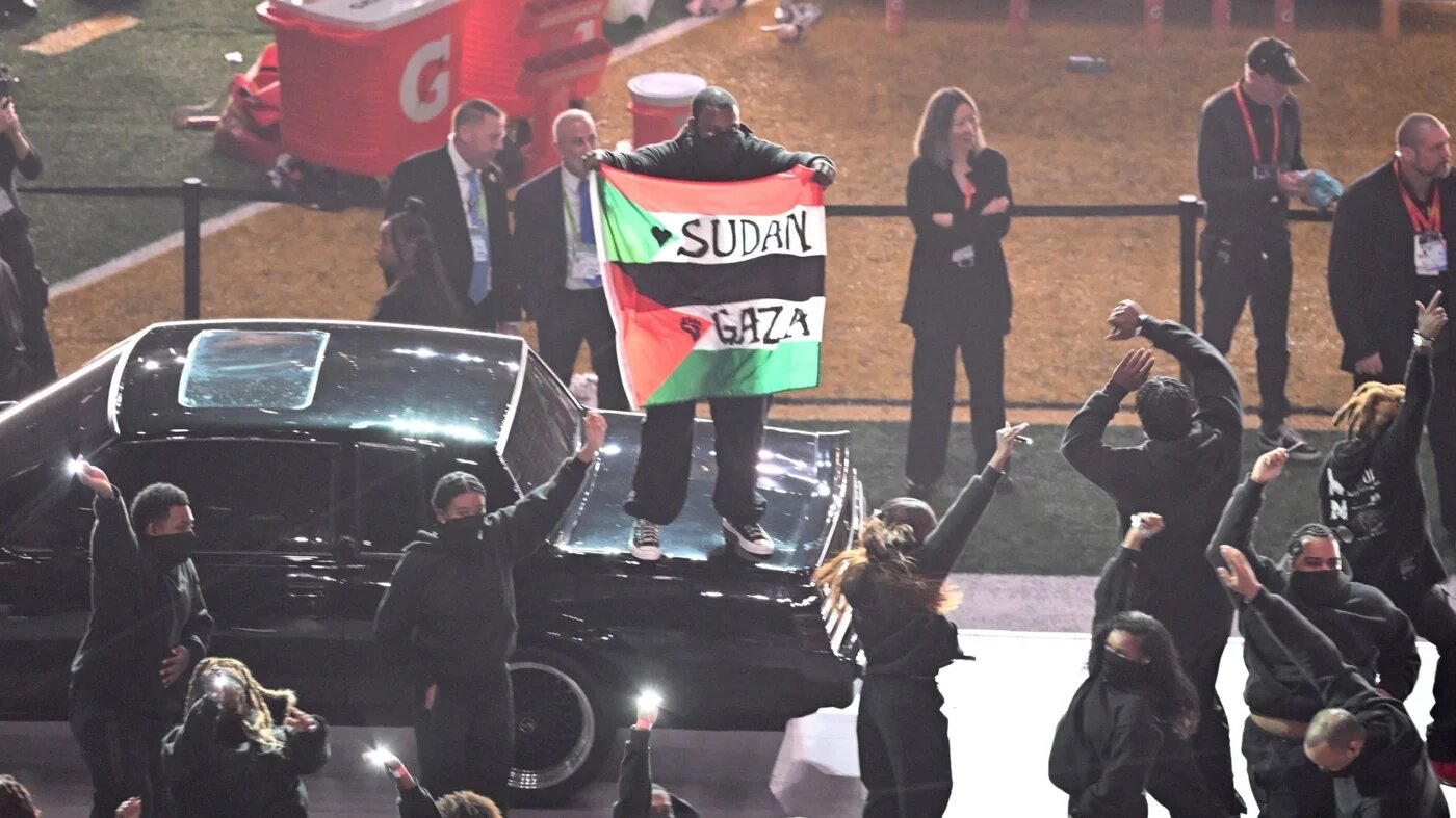 Protester holding combined Palestinian and Sudanese flags during Kendrick Lamar's Super Bowl LIX halftime show at Caesars Superdome, New Orleans, 9 February 2025 (Chandan Khanna/AFP)