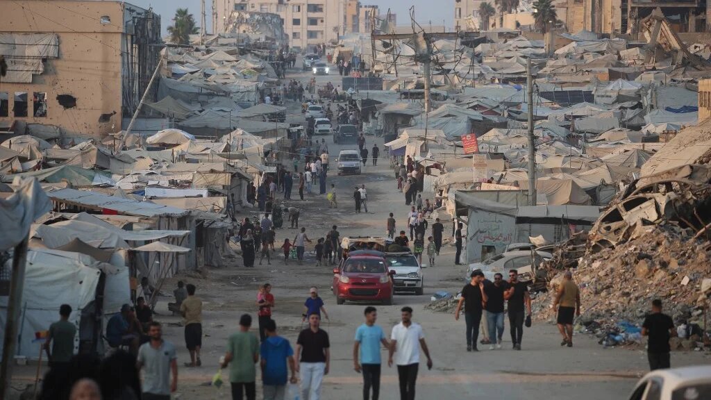 Displaced Palestinians walk past tents and destroyed buildings near the beach front in Gaza City on 14 August 2026 (Eyad Baba / AFP)