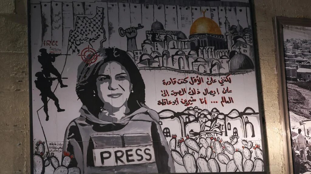 A mural depicting slain journalist Shireen Abu Akleh is illuminated with headlights on a street in the Arab town of Umm Al-Fahm on 5 September 2022 (AFP)