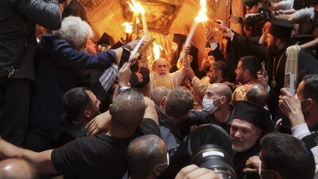 Greek Orthodox Patriarch of Jerusalem Theophilos III holds candles as Christians gather around the edicule, during the Holy Fire ceremony at Jerusalem's Holy Sepulchre church (AFP)