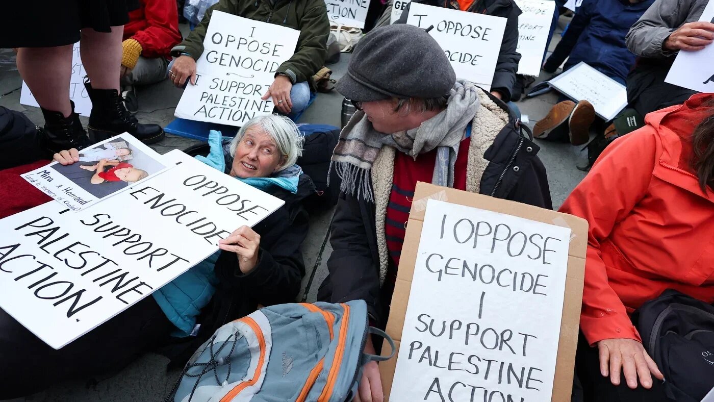 Protesters hold placards at a demonstration against the British government’s ban on Palestine Action, at Trafalgar Square in London on 4 October 2025 (Reuters)