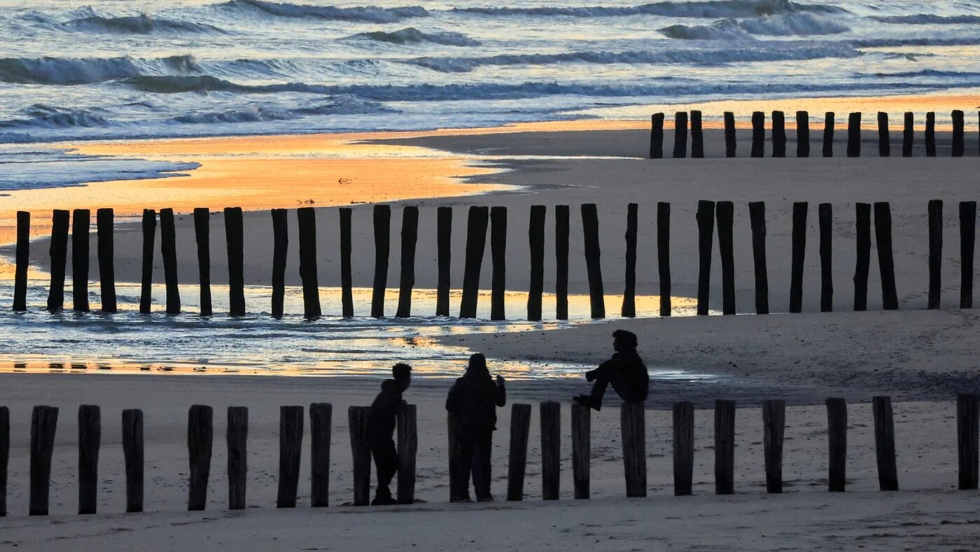 A view of migrants on the beach at sunrise after a failed attempt to cross the Channel to the UK on a small boat, in Sangatte, near Calais, France, 10 August 2023 (Reuters)