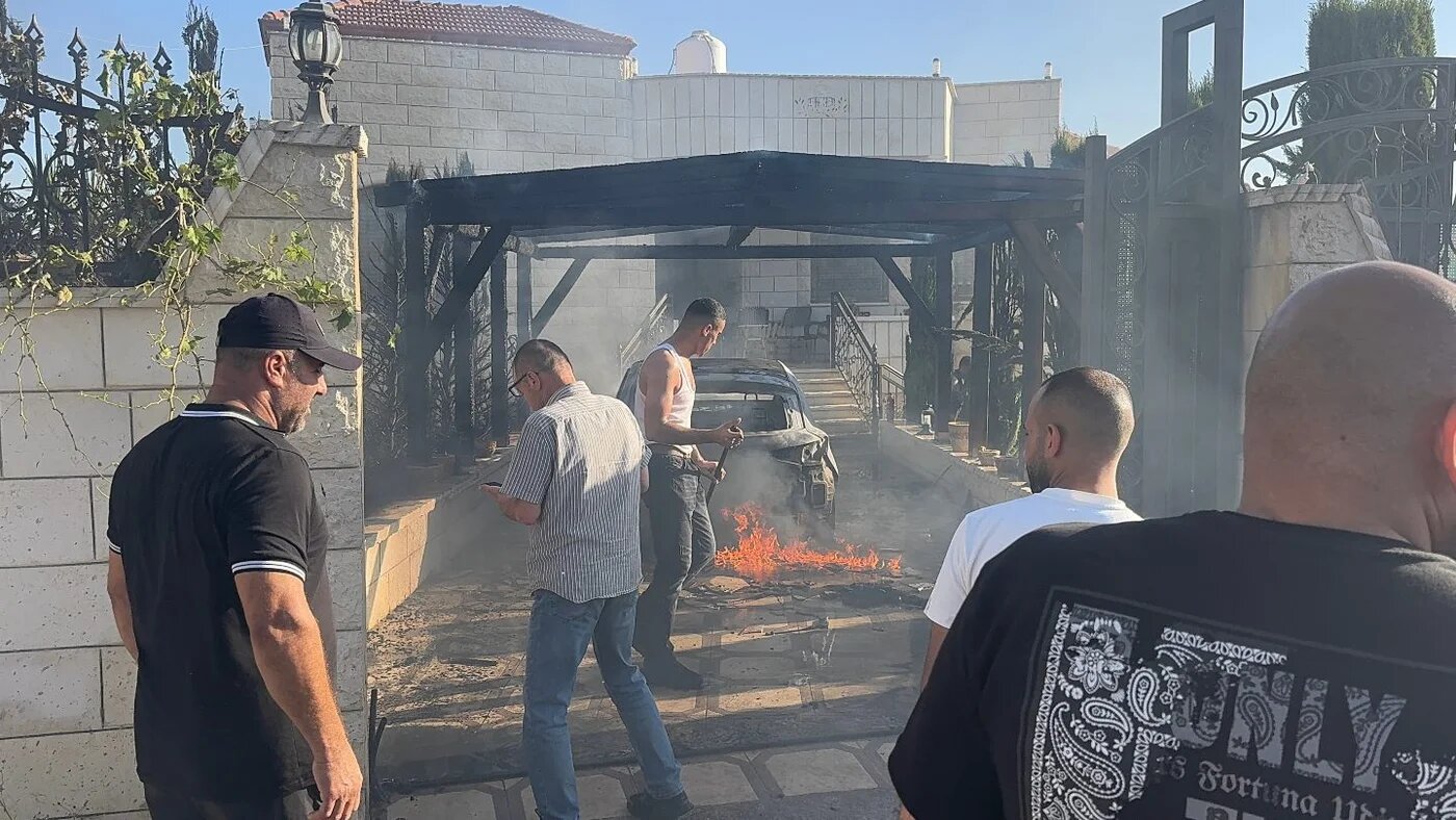Residents douse flames engulfing a car outside a home attacked by Israeli settlers in the Palestinian village of Sarra, southwest of Nablus in the occupied West Bank (Atiq/Middle East Eye)