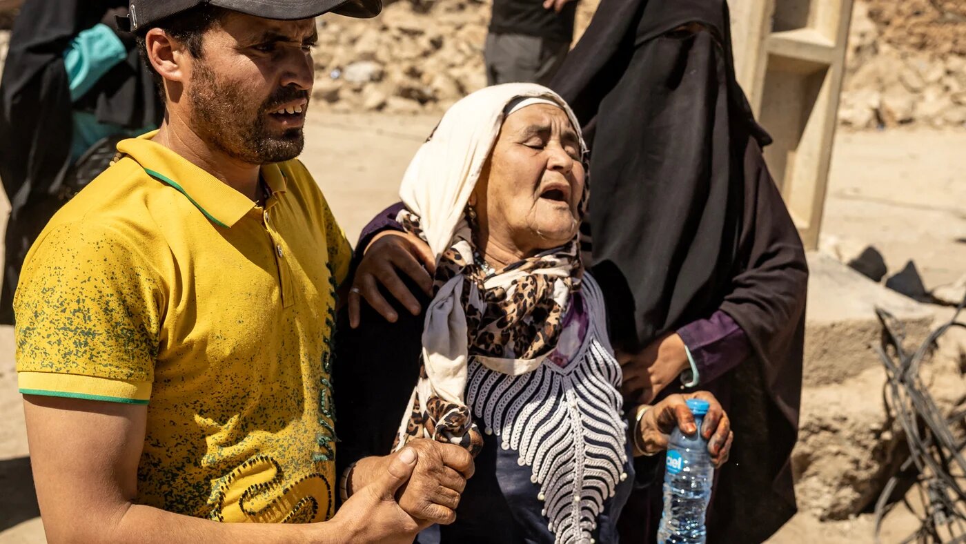 A woman is helped as she reacts to the death of relatives in an earthquake in the mountain village of Tafeghaghte, southwest of Marrakech, on 10 September 2023 (AFP)