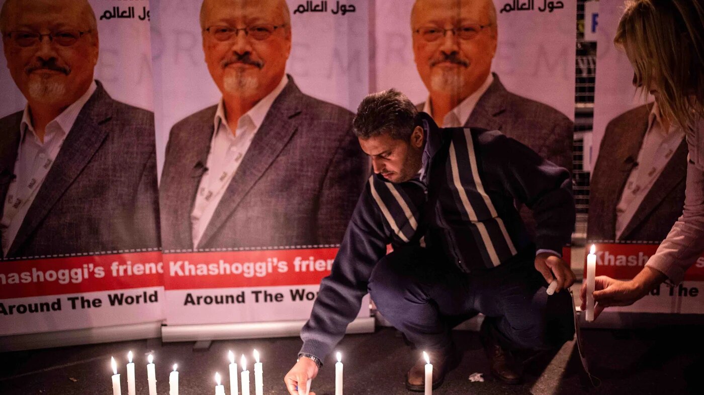 A man lights a candle by posters of slain Saudi journalist Jamal Khashoggi during a gathering outside the Saudi Arabian consulate in Istanbul on 2 October 2018 (AFP)