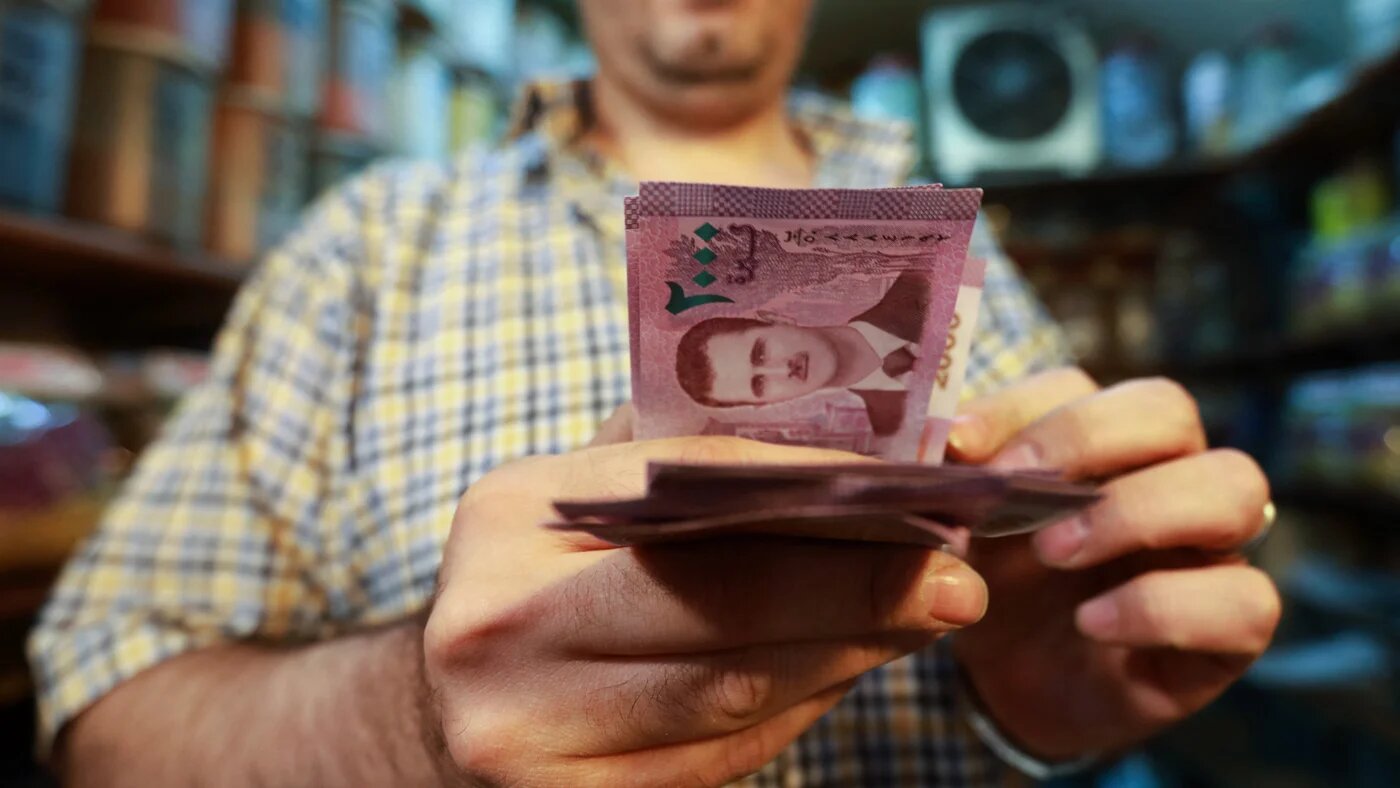 A merchant counts Syrian pound notes, bearing a portrait of the Syrian President Bashar al-Assad, at the Bzourieh market in the centre of the Syrian capital Damascus on 11 September 2019 (AFP)