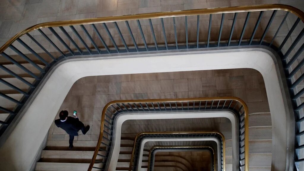 Un fonctionnaire descend les escaliers avant la visite du président français au Centre de crise et de soutien du ministère français des Affaires étrangères, au Quai d’Orsay, à Paris (AFP/François Mori)