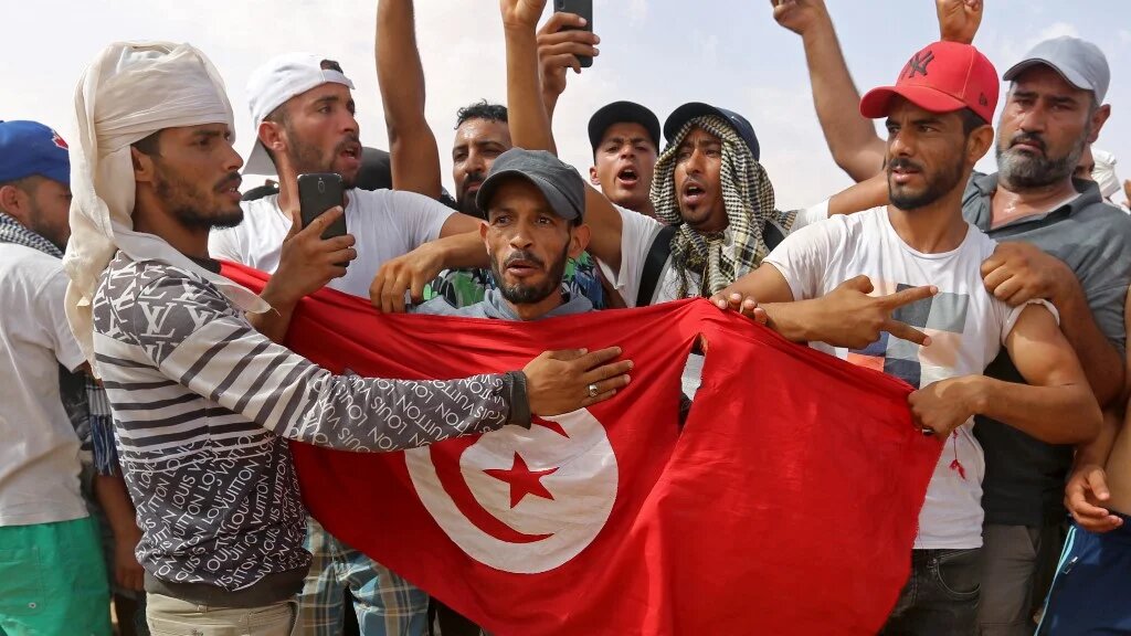 Des manifestants agitent le drapeau tunisien pendant un sit-in sur un site de production de pétrole à El Kamour, dans le sud du pays, le 16 juillet 2020 (AFP)