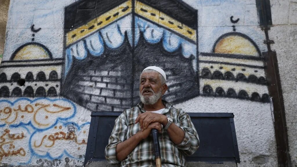 A Palestinian man sits in front of a mural paintings of the holy Kaaba,in Gaza City on 27 July 2020. (AFP)
