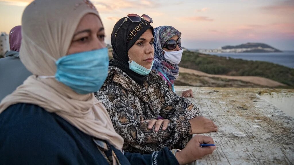 Sur la terrasse d’un immeuble, des employées marocaines de Fnideq regardent vers l’enclave de Ceuta, le 28 août 2020 (AFP)