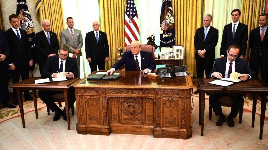 Donald Trump watches as Kosovo Prime Minister Avdullah Hoti (R) and Serbian President Aleksandar Vucic (L) sign an accord