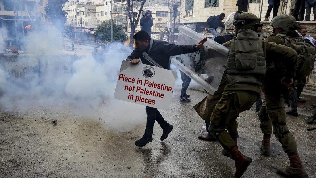 Members of the Israeli army chase a Palestinian protester following a demonstration to remember the 1994 Ibrahimi Mosque massacre, in the West Bank's Hebron, on 25 February 2022 (AFP)