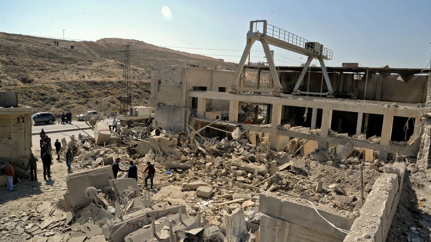 A handout picture released by the official SANA on March 7, 2022, shows people inspecting a damaged building following Israeli missile strikes before dawn near the capital Damascus. (AFP)