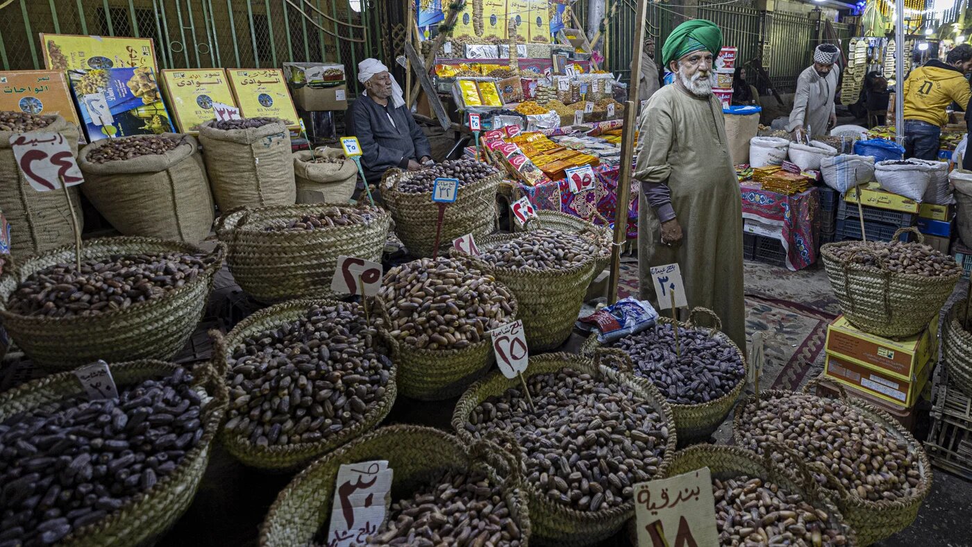 An Egyptian vendor sells dates and dried fruits at a traditional market in the Egyptian capital Cairo's central Sayyida Zeinab district late on 30 March 2022 (AFP)