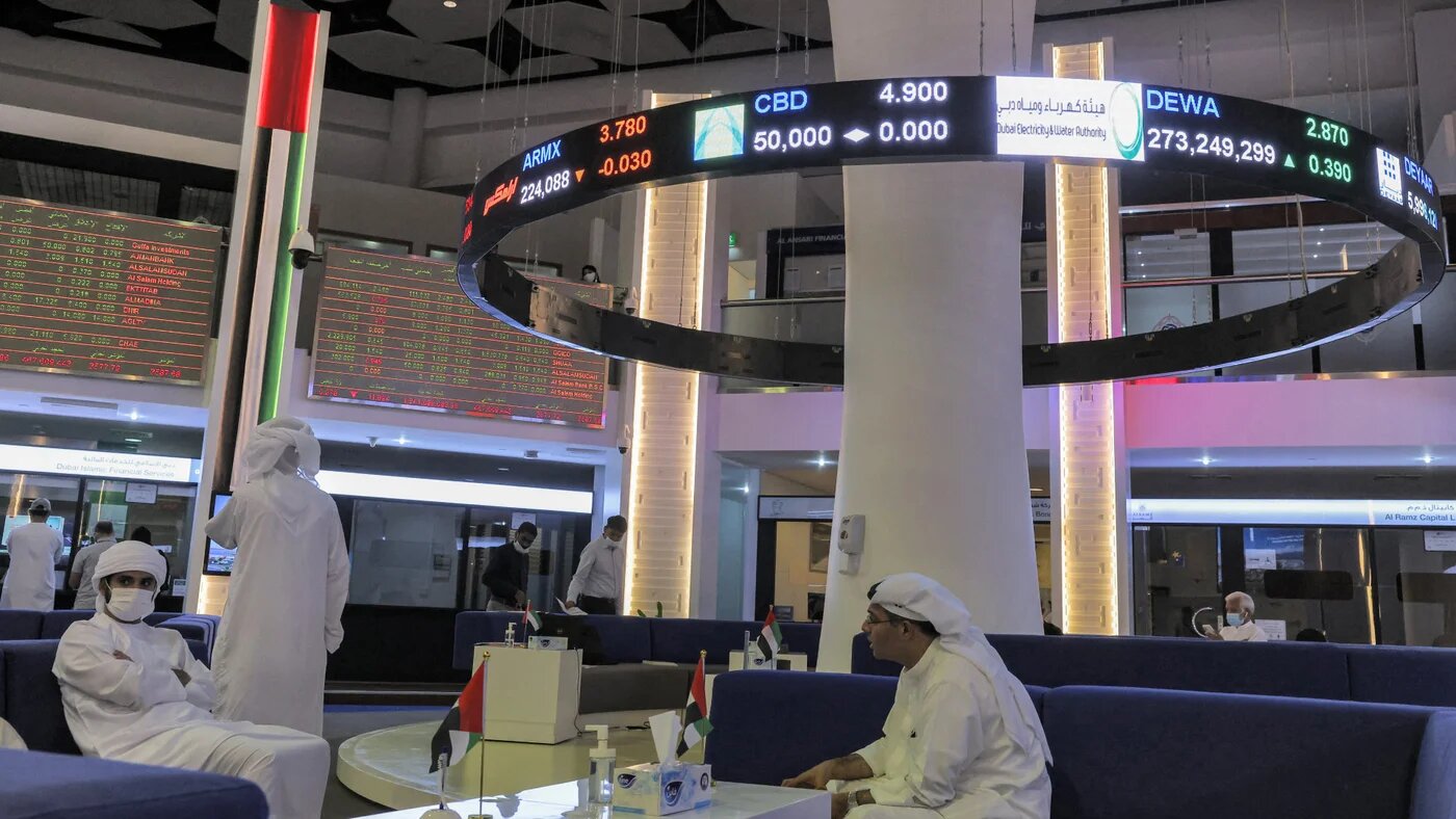 Investors sit beneath stock displays at the Dubai Financial Market on 12 April 2022. As tensions escalate between Israel and Iran, Gulf economies face growing uncertainty (Giuseppe Cacace/AFP)
