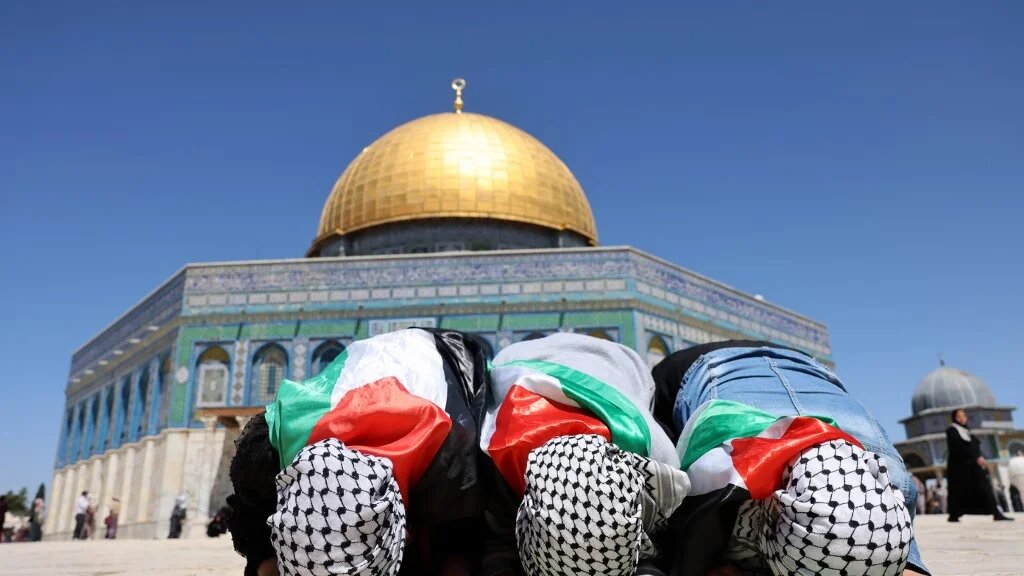 De jeunes Palestiniennes, portant le drapeau national et le keffieh, prient devant le dôme du Rocher à la mosquée al-Aqsa dans la vieille ville de Jérusalem (AFP)
