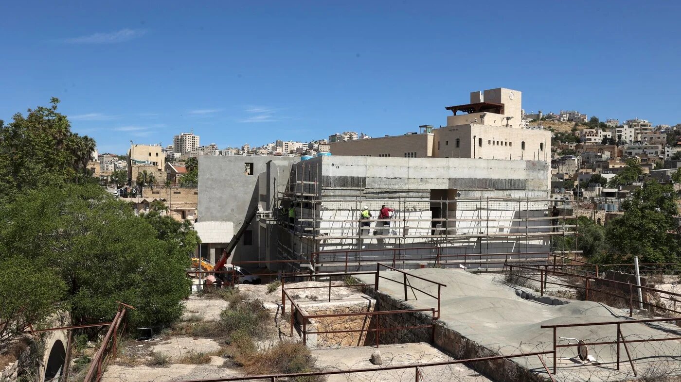 Builders work on new constructions in a settlement zone on a site where the old central bus station for the Hebron Governorate formerly stood on 8 May 2022 (AFP)