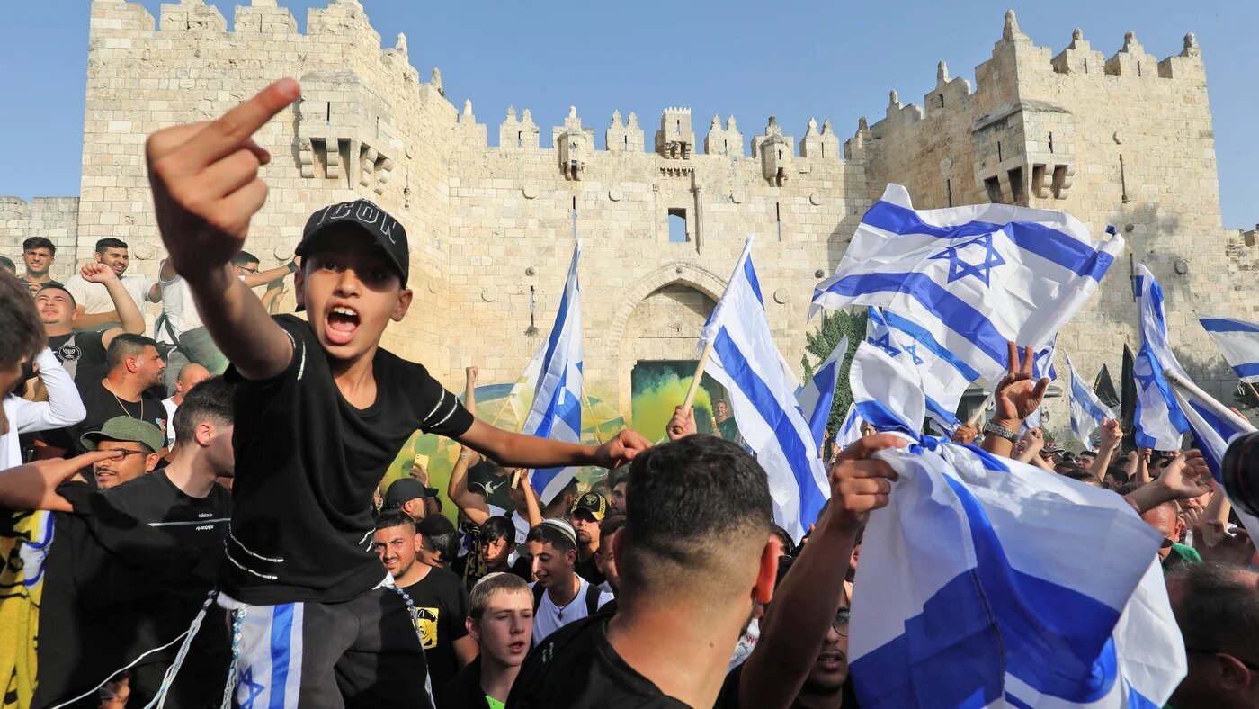 Demonstrators gesture as they gather with Israeli flags during the 'flag march' outside the Old City's Damascus Gate on 29 May (AFP)
