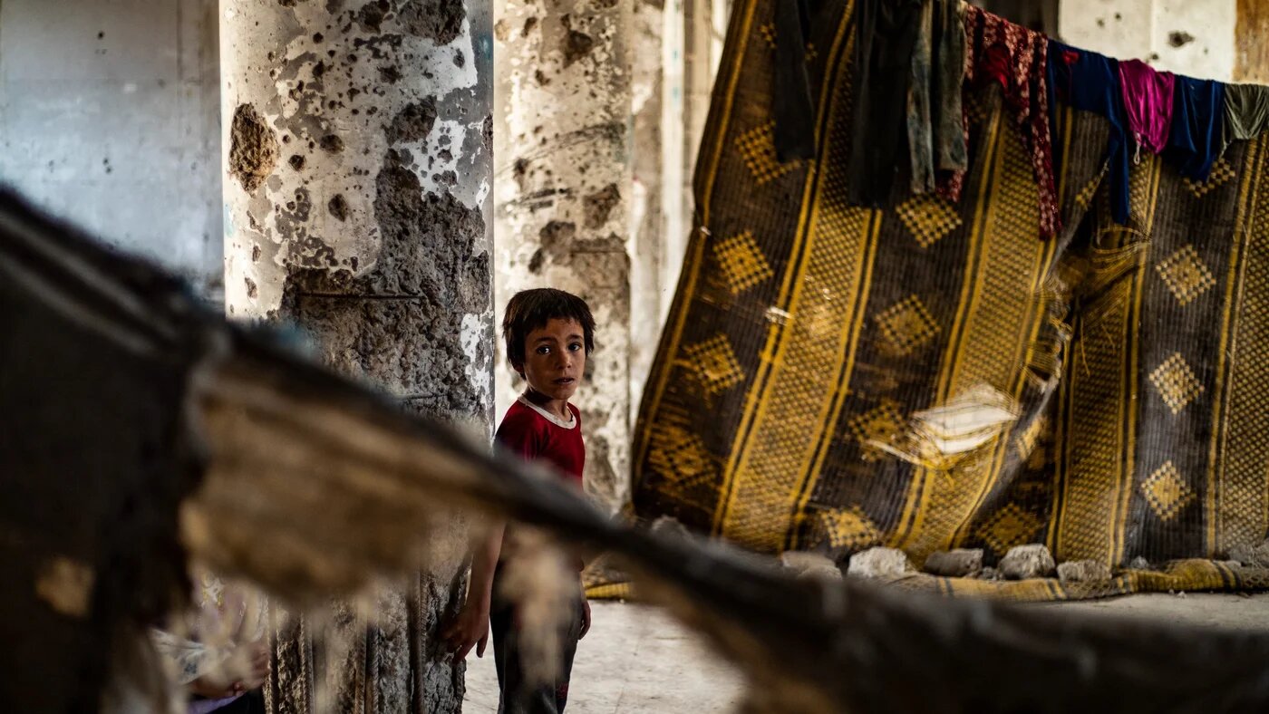 A Syrian boy, displaced with his family from Deir Ezzor, inside the damaged building where she is living in Syria's northern city of Raqqa (AFP)