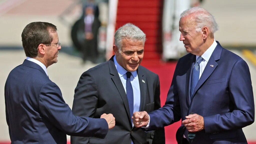 US President Joe Biden (R) bumps fists with Israel's President Isaac Herzog as caretaker Prime Minister Yair Lapid looks on, at Israel's Ben Gurion Airport in Lod near Tel Aviv, on 13 July 2022. (AFP)