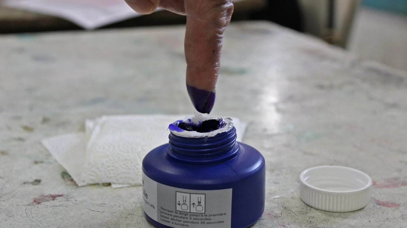 A Tunisian man dips his finger in ink after voting in a referendum on a draft constitution put forward by the country's President, at a polling station in Kasserine, on 25 July 2022 (AFP)