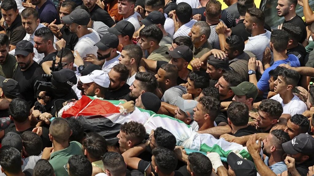 Mourners carry the body of Ibrahim al-Nabulsi, who was killed in an Israeli raid, during a funeral procession in the West Bank city of Nablus on 9 August 2022 (AFP)