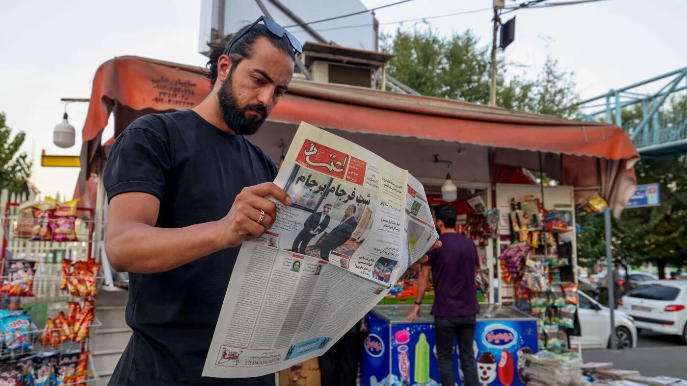 Un homme lit le journal iranien Etemad, dont le titre en une indique en farsi « La nuit de la fin du Plan d’accord conjoint », accompagné d’une photo du ministre iranien des Affaires étrangères Hossein Amir-Abdollahian et de son adjoint Ali Bagheri Kani, chargé des négociations sur le nucléaire, le 16 août 2022 à Téhéran (AFP)
