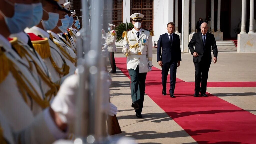 Le président français Emmanuel Macron marche avec le président algérien Abdelmadjid Tebboune, à l’aéroport d’Alger le 27 août 2022 (AFP/Ludovic Marin)