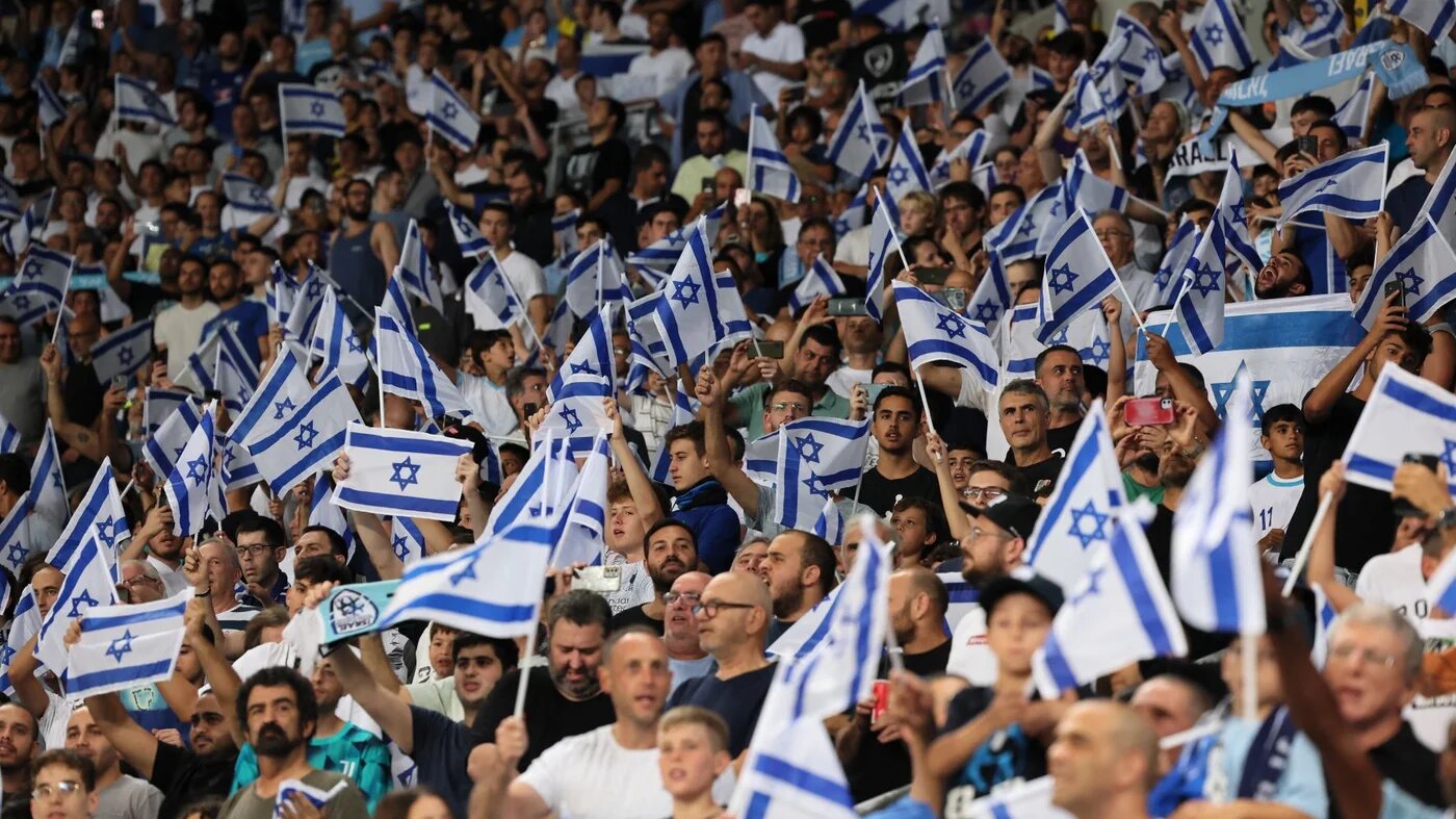 Israel supporters wave the national flag during the UEFA Nations League - League B Group 2 - football match between Israel and Albania at the at the Bloomfield Stadium, in Tel Aviv on September 24, 2022 (AFP)