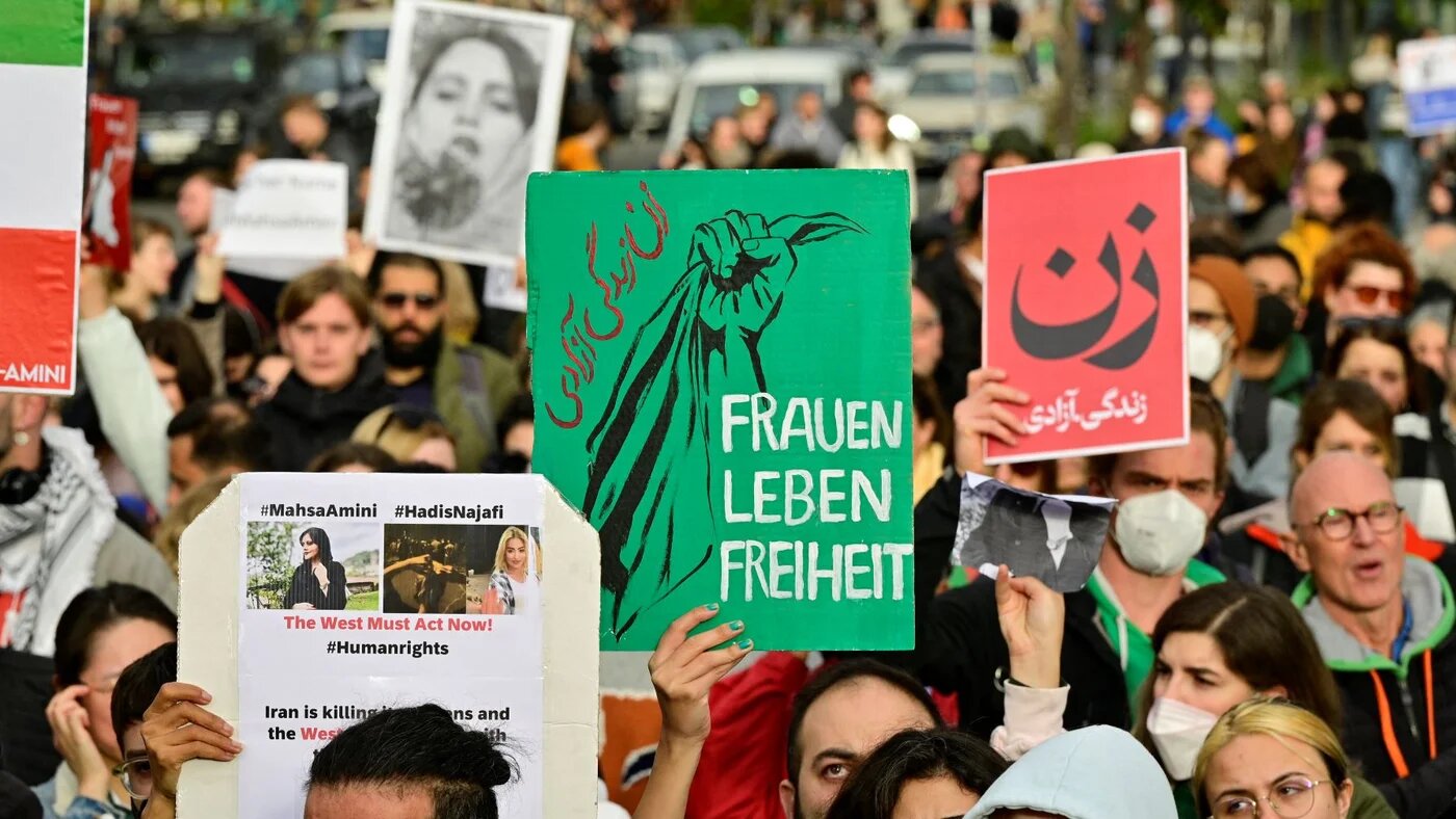 Demonstrators hold placards in support of women and the Iranian protesters, on September 28, 2022 near Berlin's landmark Brandenburg Gate (AFP)