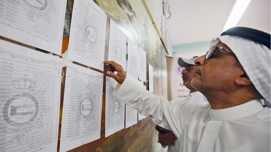 Kuwaiti men check voting lists at a polling station during parliamentary elections in Kuwait City on 29 September 2022 (AFP)