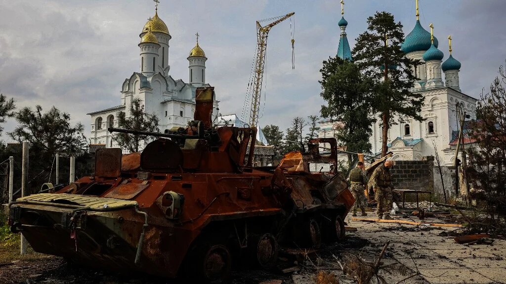 Photograph taken on 30 September 2022 shows Ukrainian servicemen walking next to a destroyed Russian Army APC in a yard of Burial Shroud of the Mother of God Orthodox Church on the bank of the Seversky Donets River near the town of Sviatohirsk, Donetsk region (AFP)