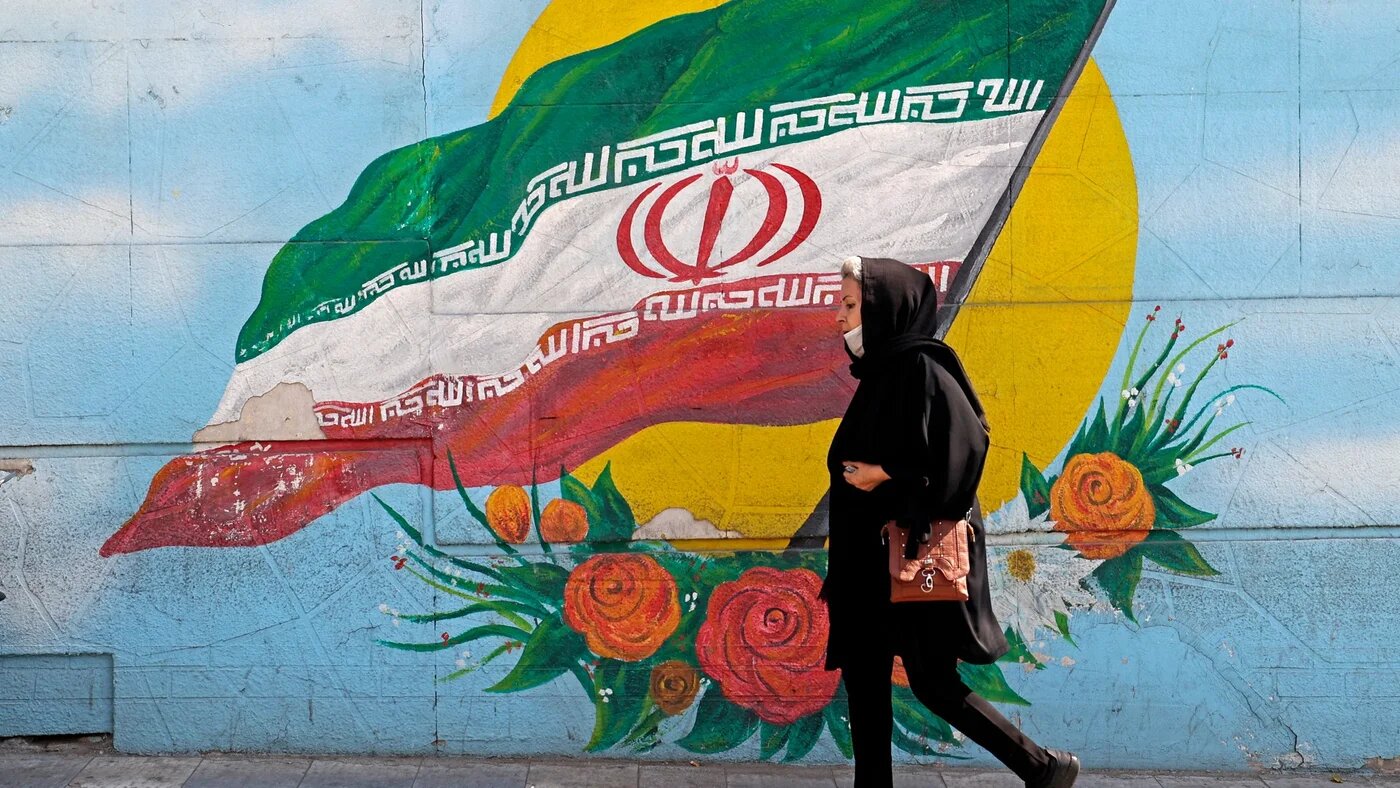 A woman walks past a mural in Tehran, on 11 October (AFP)