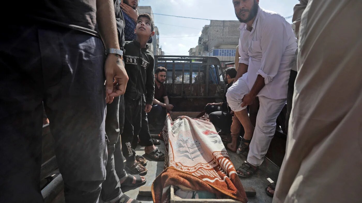 Syrians gather around the body of a victim of the battles between rival Syrian factions competing for power in al-Bab on 14 October (AFP)