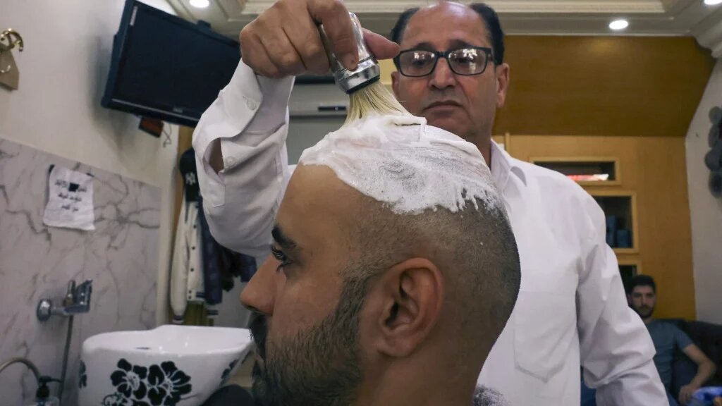 A Palestinian man has his hair shaved at a salon in Hebron city in the occupied West Bank, on 16 October 2022, following a trend which spread on social media in solidarity with a bald-headed Palestinian reported to be behind an attack on an Israeli checkpoint in occupied East Jerusalem (AFP)
