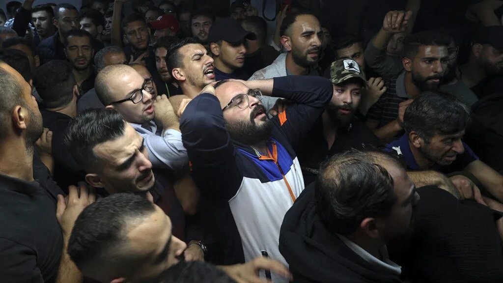 Men mourn near a body of Palestinian at a morgue after Israeli raid in Nablus, in the occupied West Bank on early 25 October 2022 (AFP)