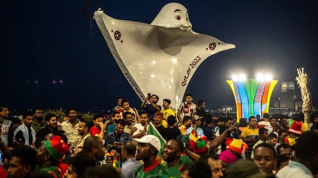 People gather in front of the offical mascot La'eeb at Corniche promenade in Doha on 18 November 2022, ahead of the Qatar 2022 World Cup football tournament (AFP)